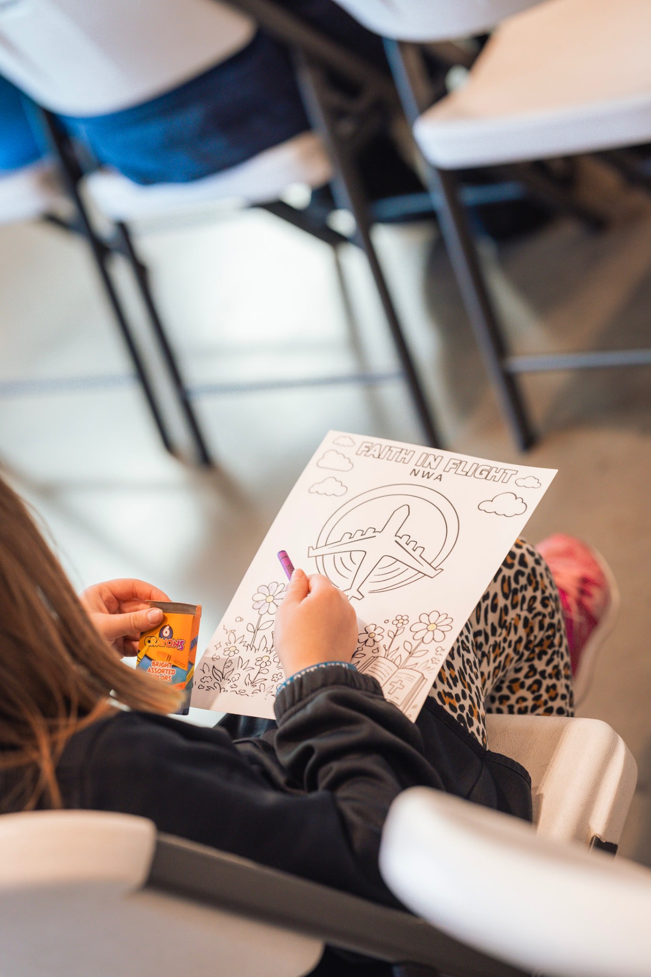 Child coloring a Faith In Flight activity sheet
