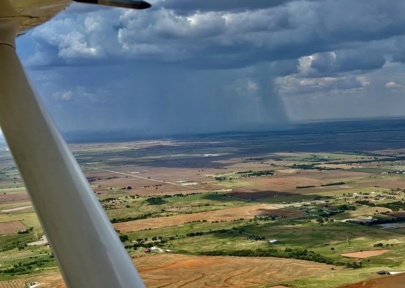 Aerial view of farmland with a distant rain shower