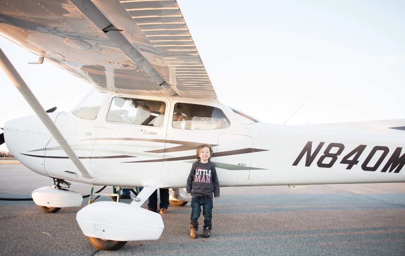 Young aviator beside a Cessna N840M on the ramp at sunset