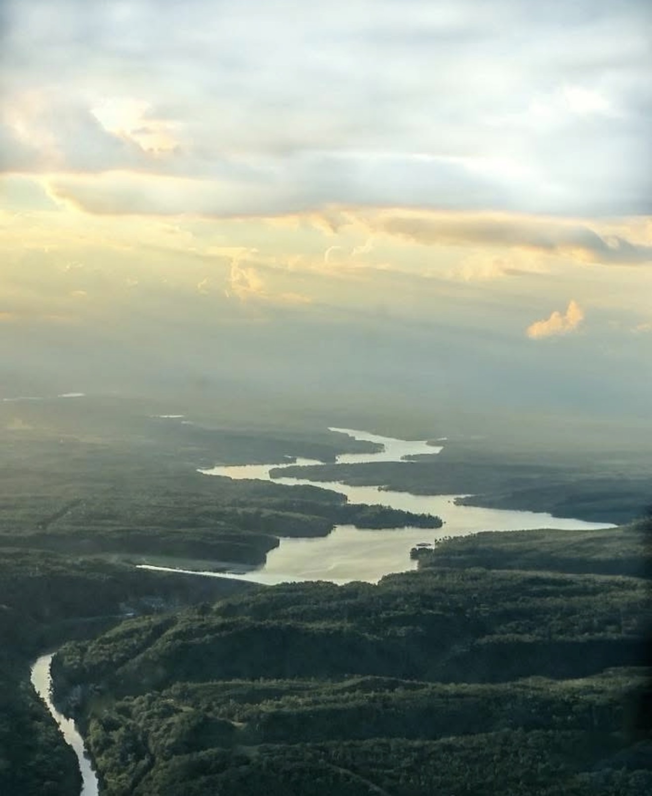 Golden hour aerial view of a winding river through forested hills