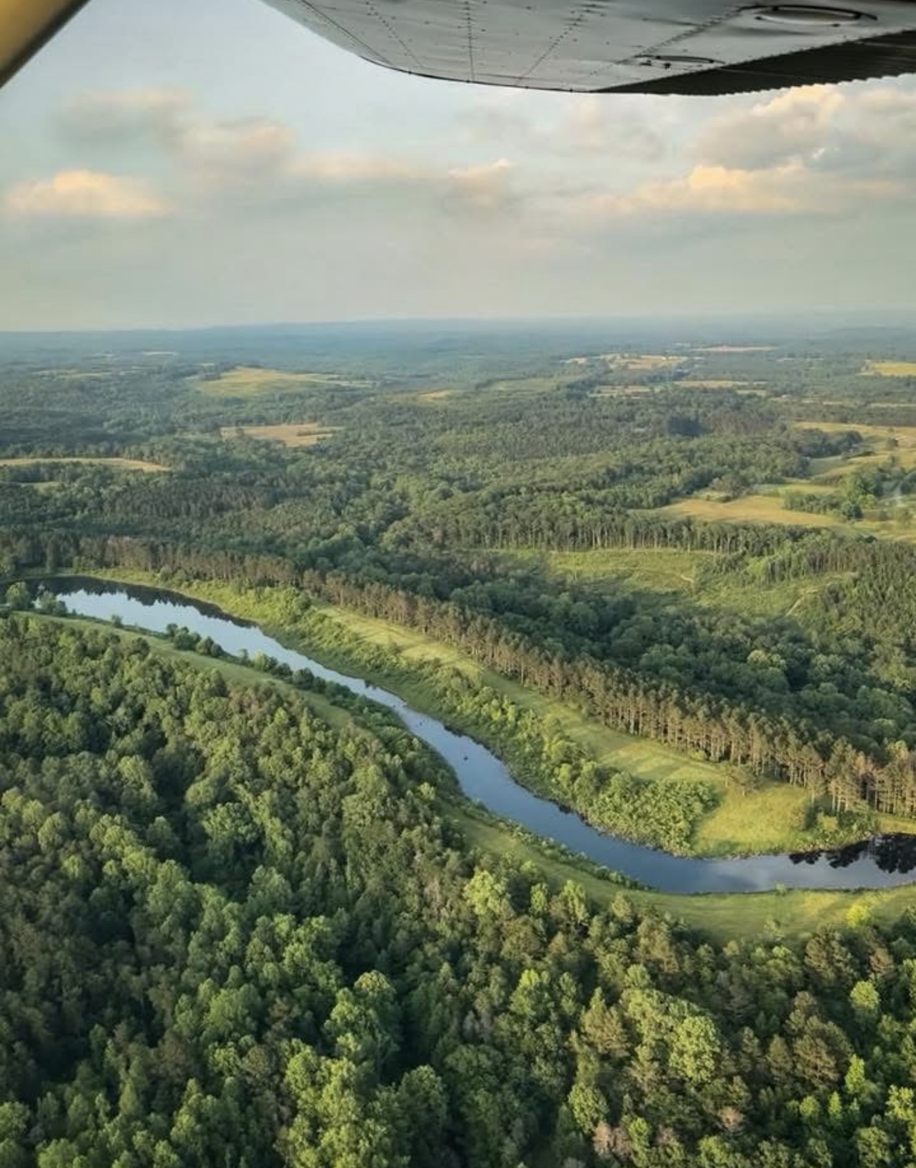 Aerial view from a Cessna wing over green countryside and a river bend