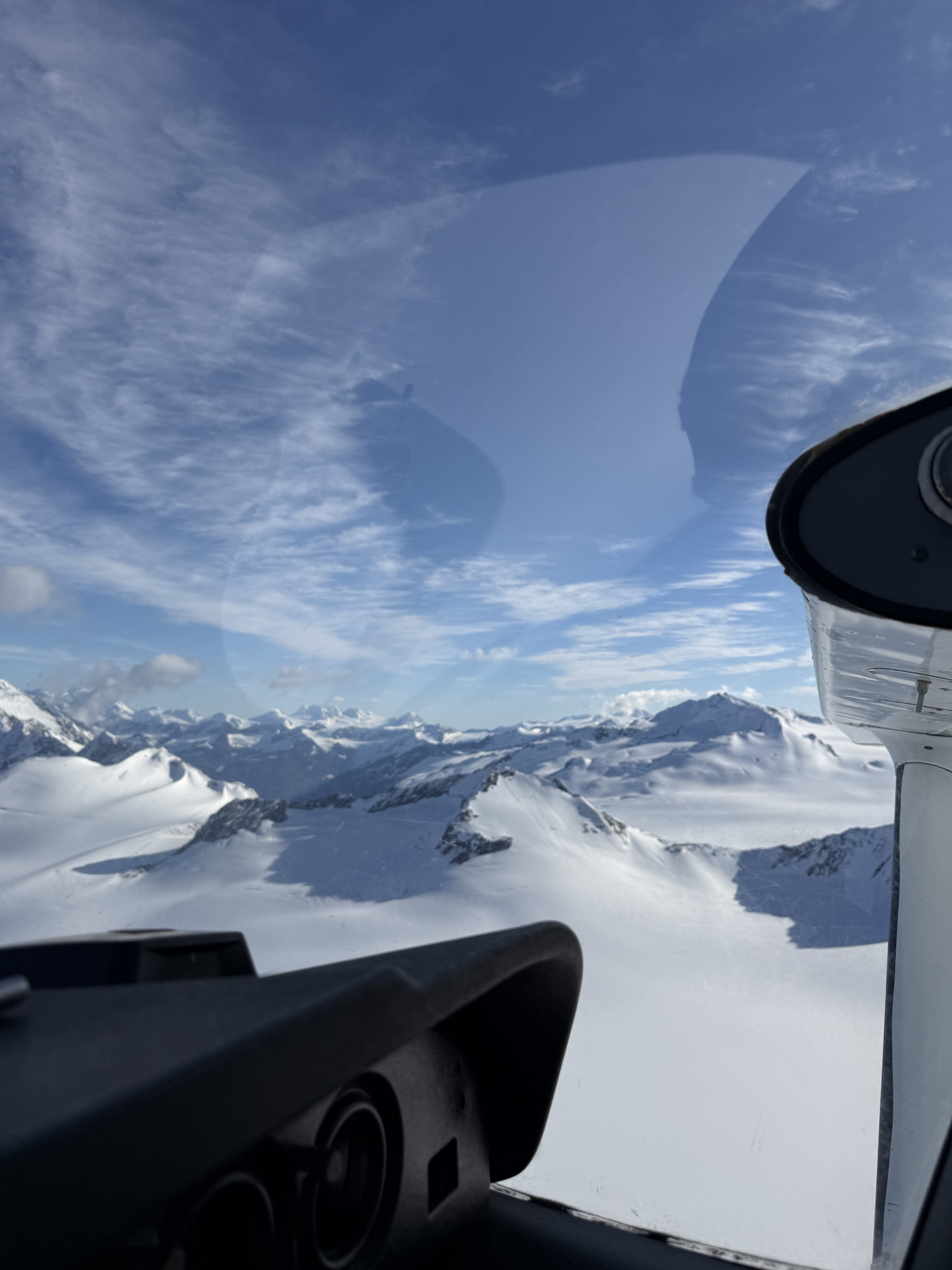 Cockpit view of snow-capped mountain ranges from a small plane