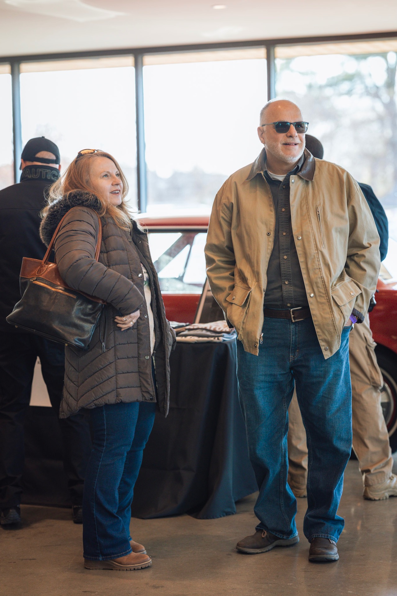 Guests mingling near a classic car display at a Faith In Flight event